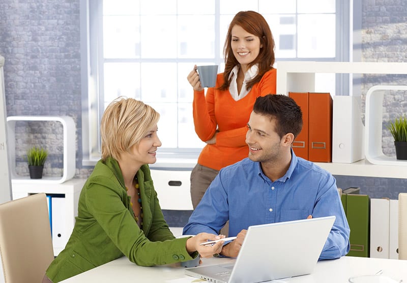 Two females and male IT consulting meeting in front of a laptop 